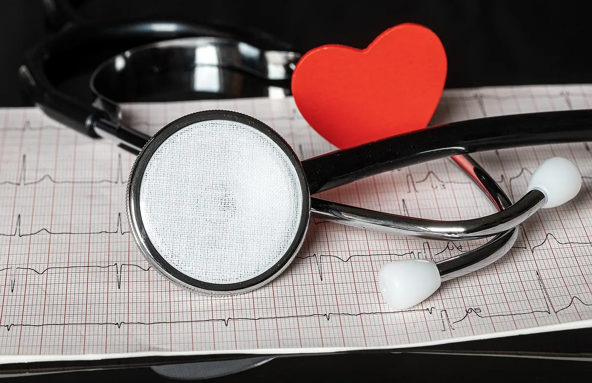Une machine ECG avec des ondes nettes, une montre Fitbit sur un poignet, un cabinet médical avec une infirmière, 80% de précision