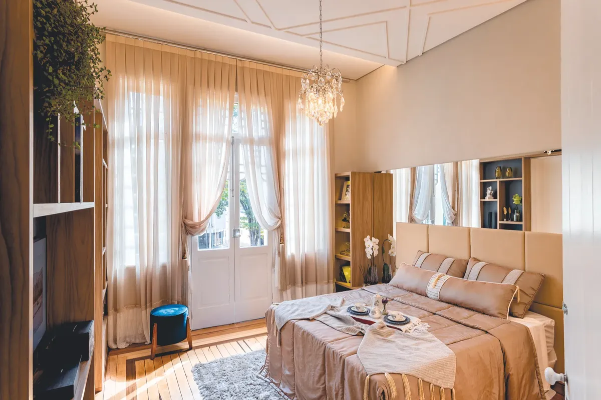 Cozy bedroom with elegant decor, soft lighting, and breakfast spread on bed, perfect for relaxation.