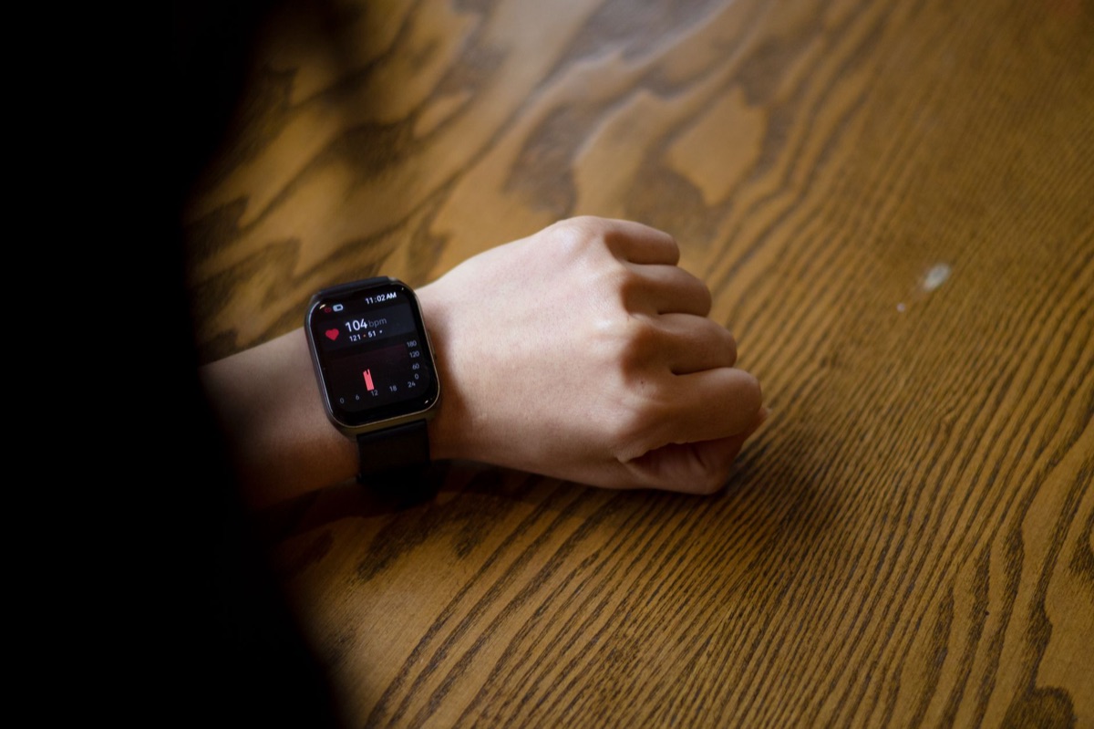 Close up of a smartwatch displaying heart rate data on its screen.