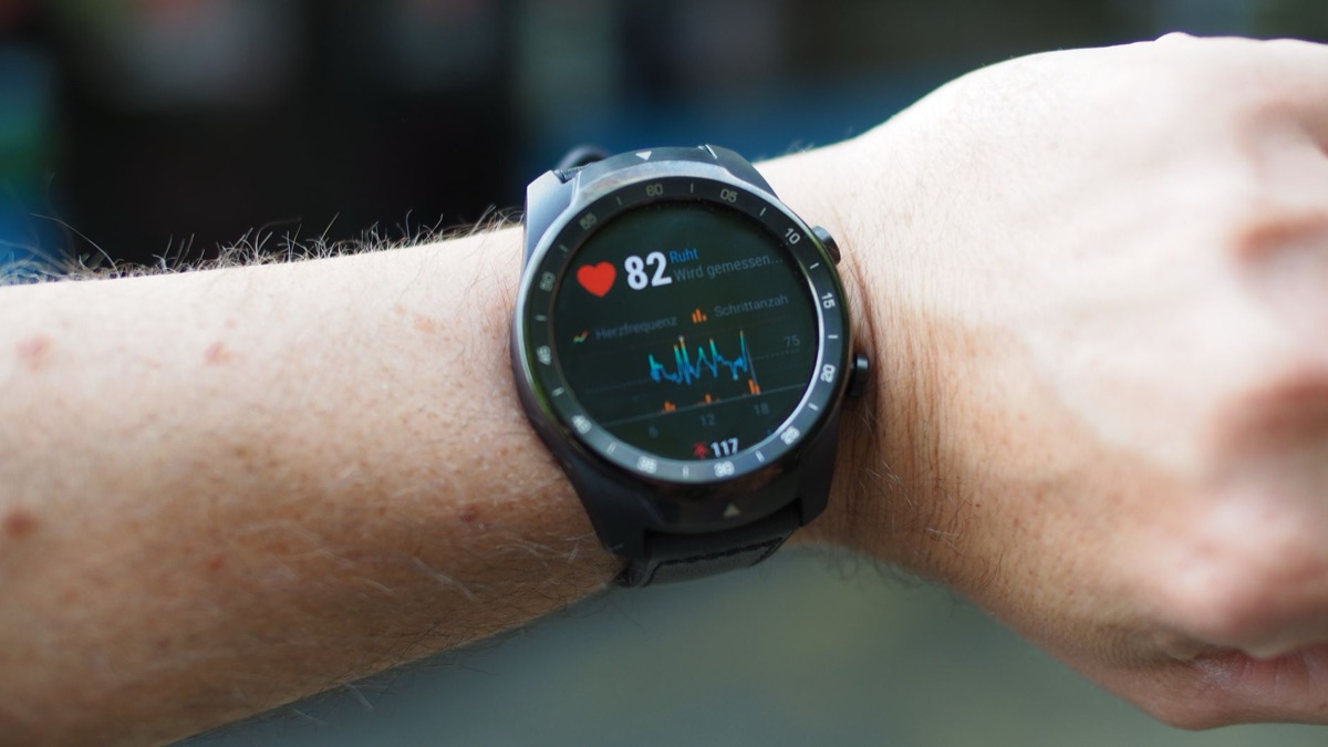 Close up of a smartwatch displaying fitness tracking data on a wrist.
