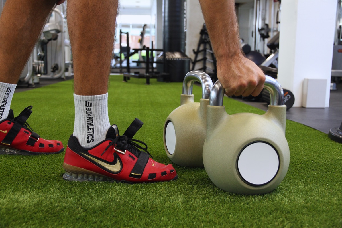 Set of heavy kettlebells and dumbbells on a gym floor.