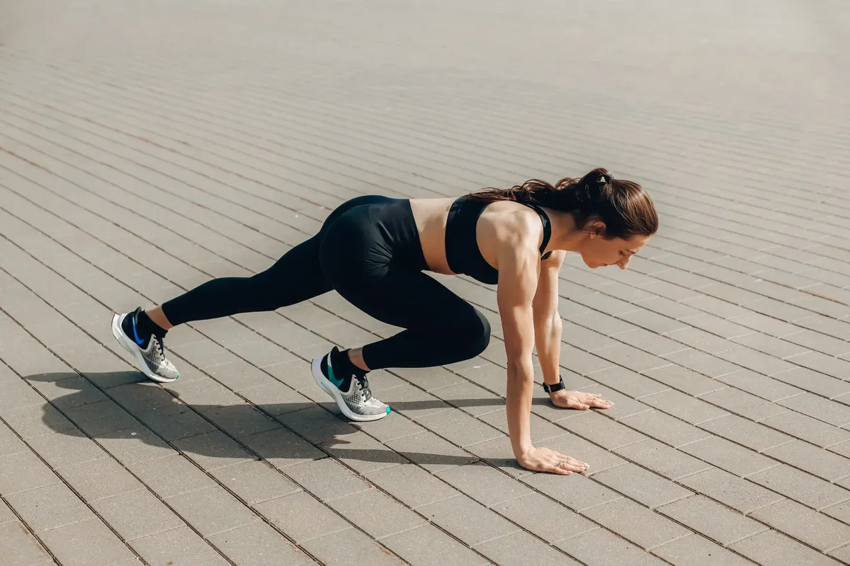 Woman in black sportswear doing an outdoor workout on a sunny day.