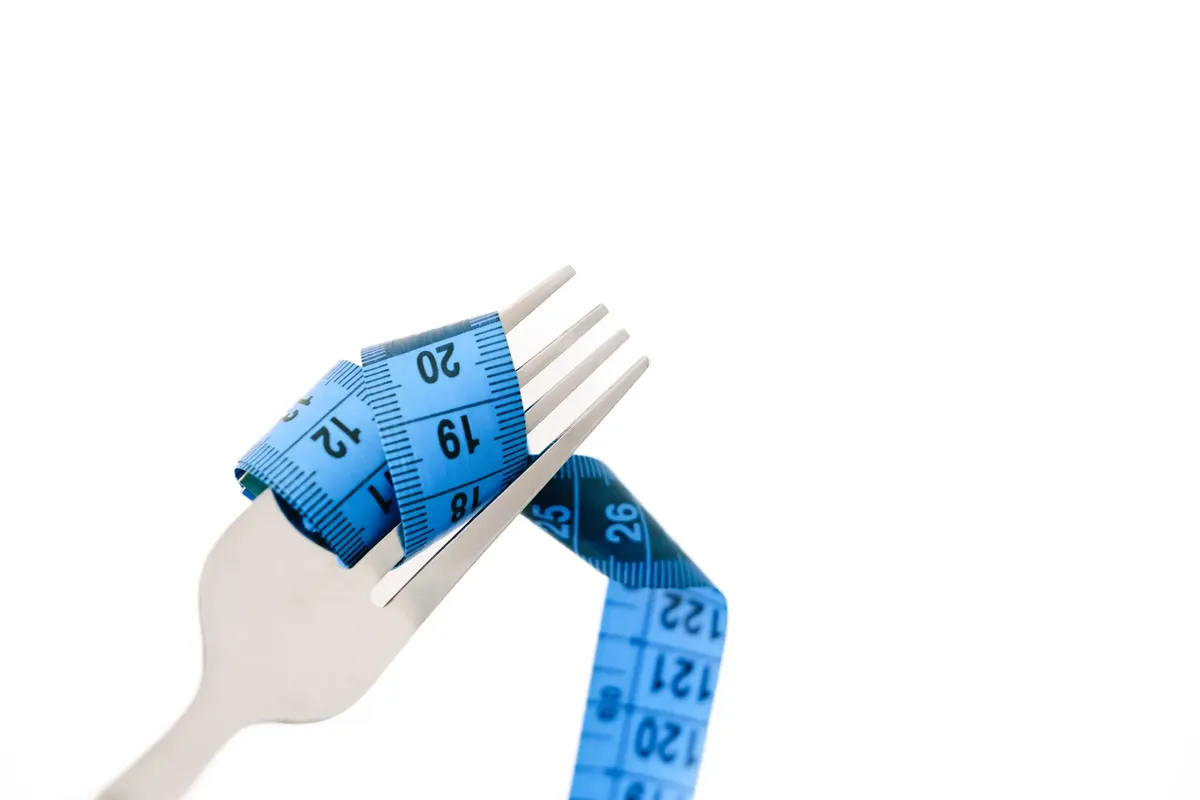 A fork wrapped with a blue measuring tape symbolizing diet and weight management.